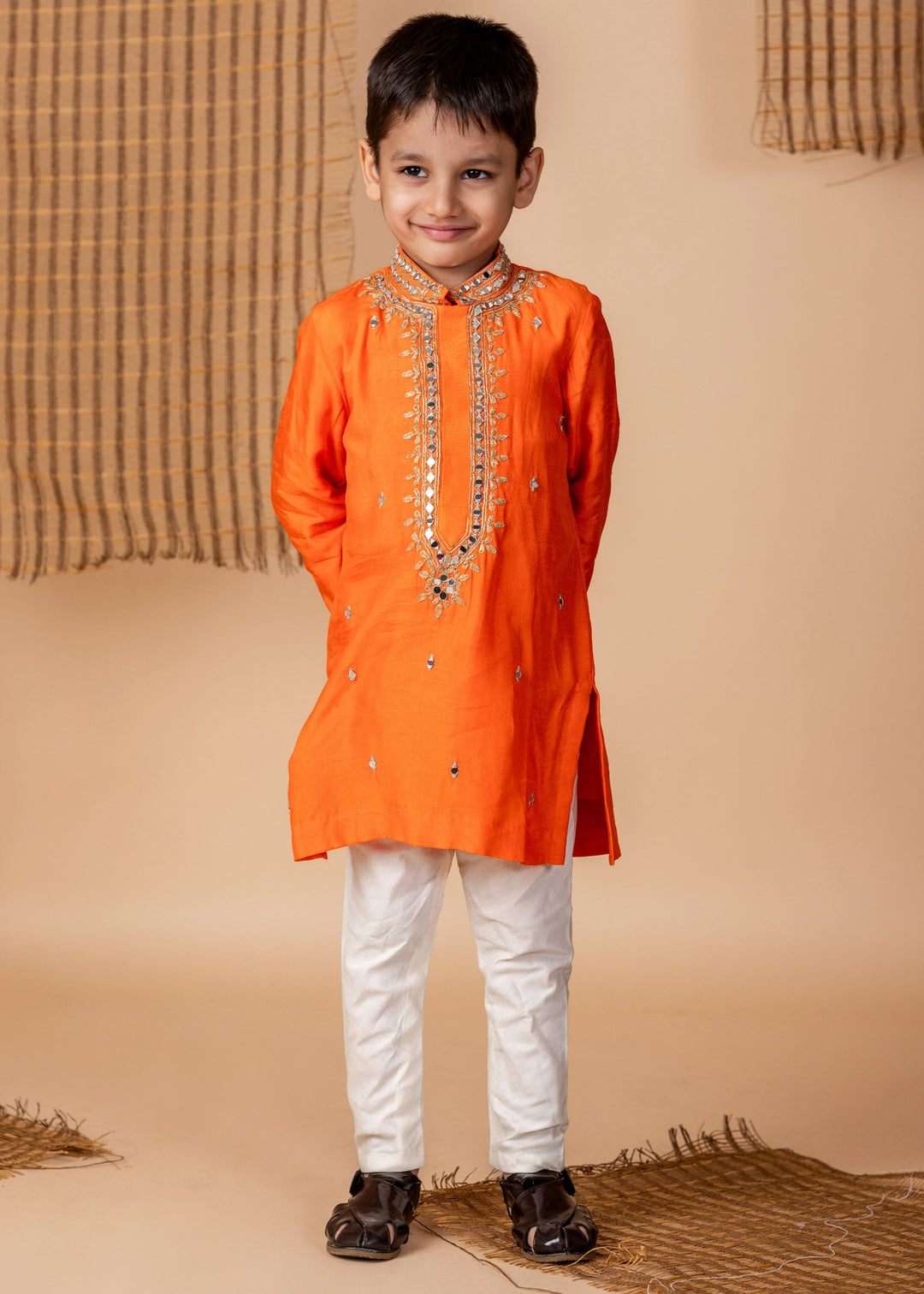 Child wearing an orange kurta with white pants